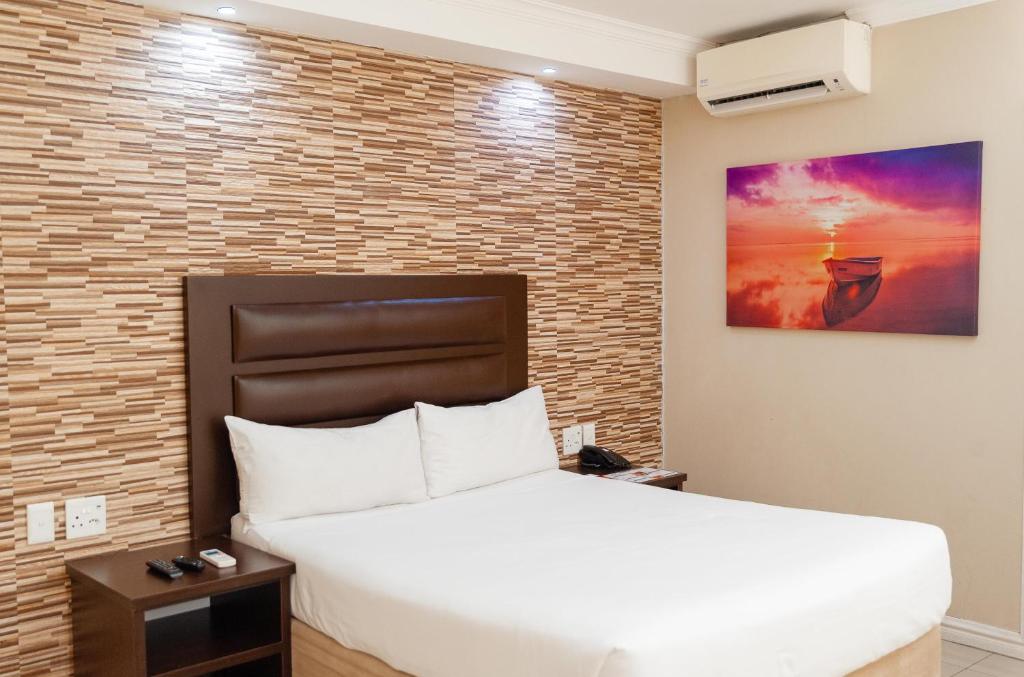 1 dormitorio con cama blanca y pared de ladrillo en Bayside Hotel 100 Pixley Kaseme Street (West Street) en Durban