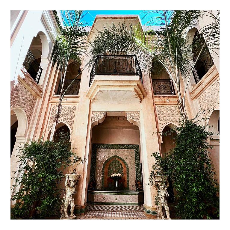 a large building with palm trees in front of it at Palais Nejma oriental in Marrakesh