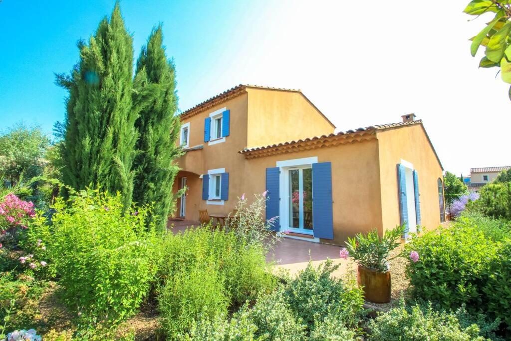 a yellow house with blue shutters in a garden at Beautiful holiday villa in Provence France in Aups