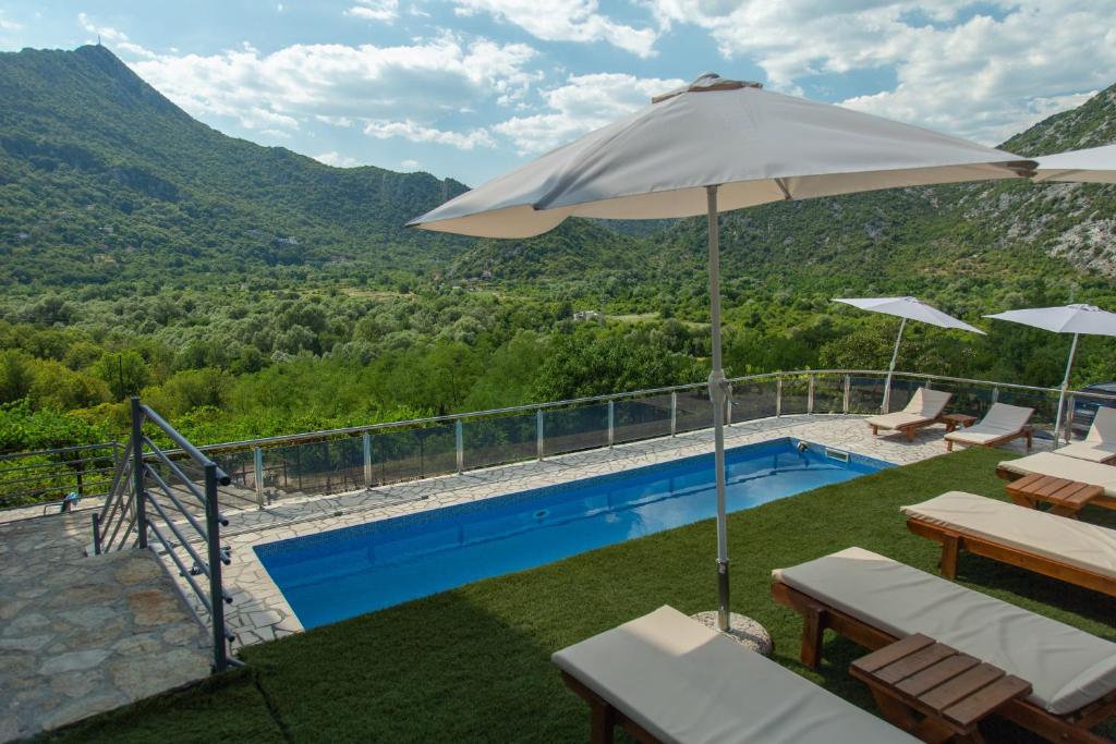 a swimming pool with an umbrella and chairs and a pool at Brioni in Virpazar