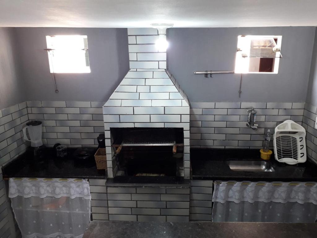 a kitchen with a brick fireplace and a sink at Casa Super CONFORTÁVEL a 8min da praia do Forte in Cabo Frio