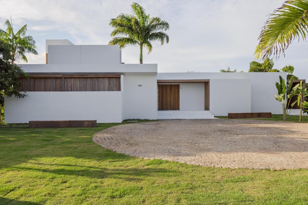 una casa blanca con una palmera delante de ella en KA BRU Beach Boutique Hotel, en Barra Grande