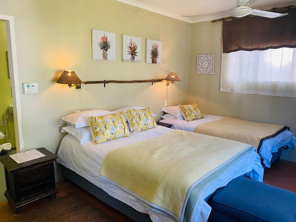 a bedroom with two beds and a window and two lamps at Wild Fig Guesthouse in White River