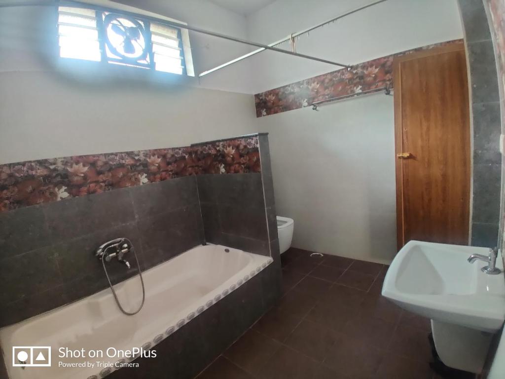 a bathroom with a tub and a toilet and a sink at Nandana Home stay in Mysore