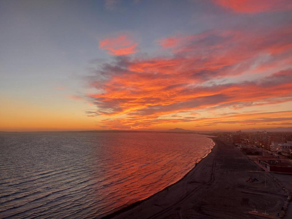 una puesta de sol sobre el océano con un cielo nublado en Sunset Beach II, en Santa Pola