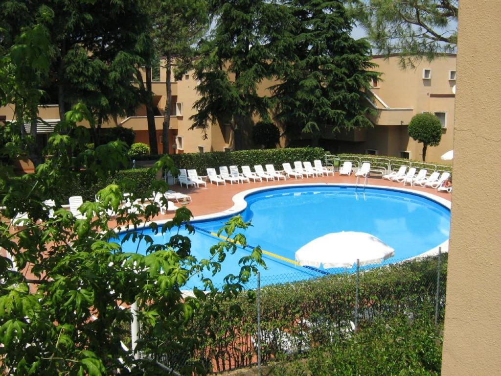 a swimming pool with chairs and an umbrella at Residence La Madonnina in Peschiera del Garda