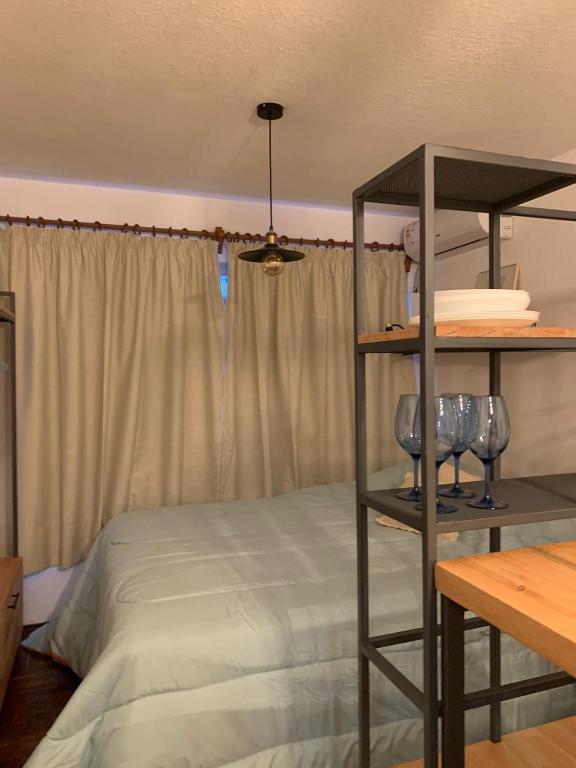 a bedroom with a bed and a shelf with glasses at Comodo monoambiente bien ubicado en Cordon in Montevideo
