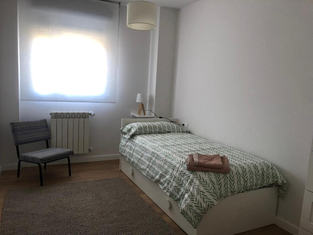 1 dormitorio con 1 cama, 1 silla y 1 ventana en TÍA NANDUCA, en Liencres