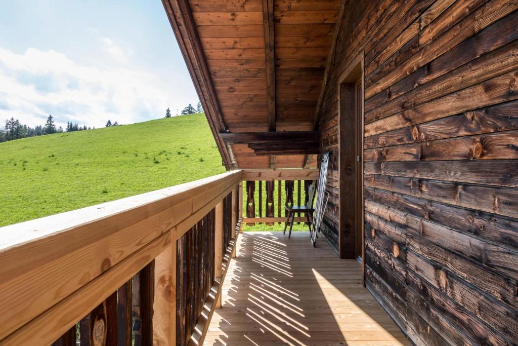 a porch of a wooden cabin with a green hill in the background at Nigglhof Apartment Maria in Redagno