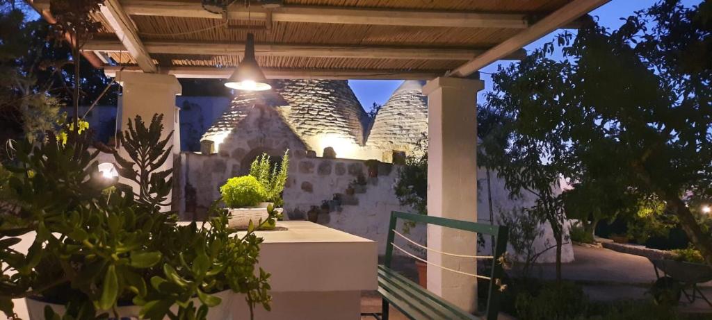 un patio sotto un pergolato con piante e un edificio di TRULLO PIETRAPOESIA a Ostuni