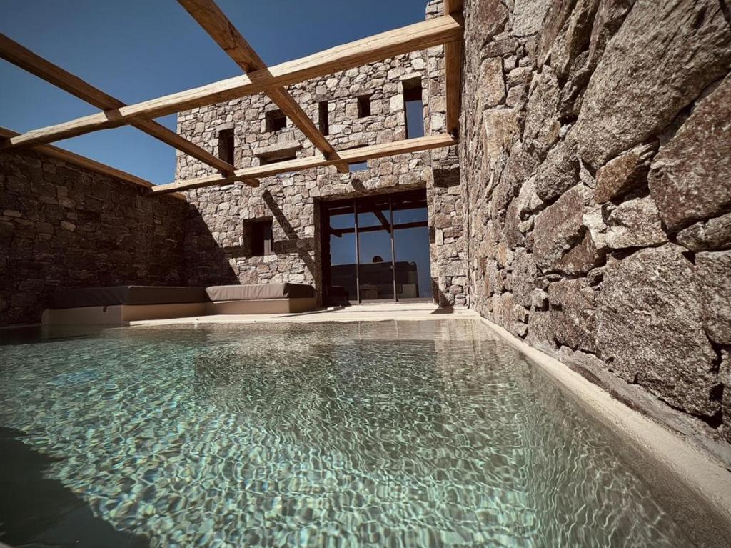 a swimming pool in a stone building with a stone wall at Ria Mar Suites in Mýkonos City