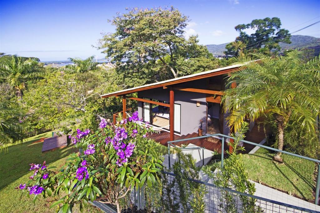uma casa numa colina com flores roxas em Studios Altos da Igrejinha em Florianópolis