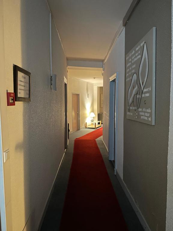 a long hallway with a red carpet on the floor at Hôtel les Platanes in Villeneuve-sur-Lot