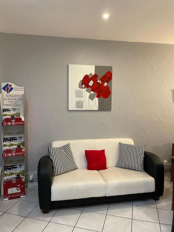 a white couch with two red pillows in a room at Hôtel les Platanes in Villeneuve-sur-Lot