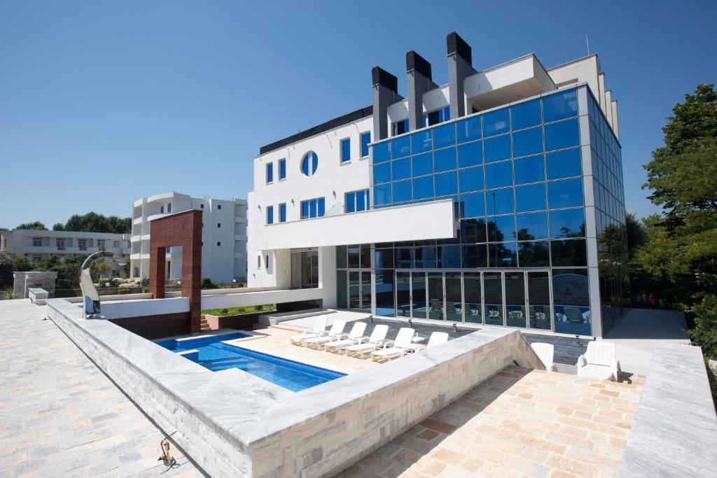 a building with a swimming pool and lounge chairs at Hotel Liana in Ulcinj