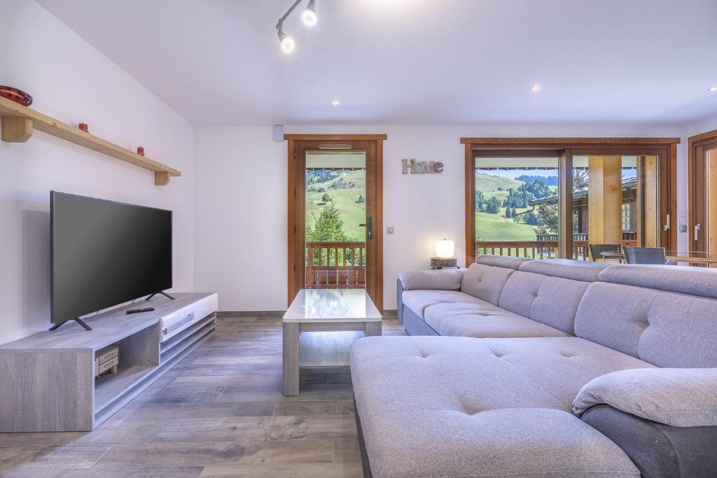 sala de estar con sofá y TV de pantalla plana en Le Samance 2 en Le Grand-Bornand