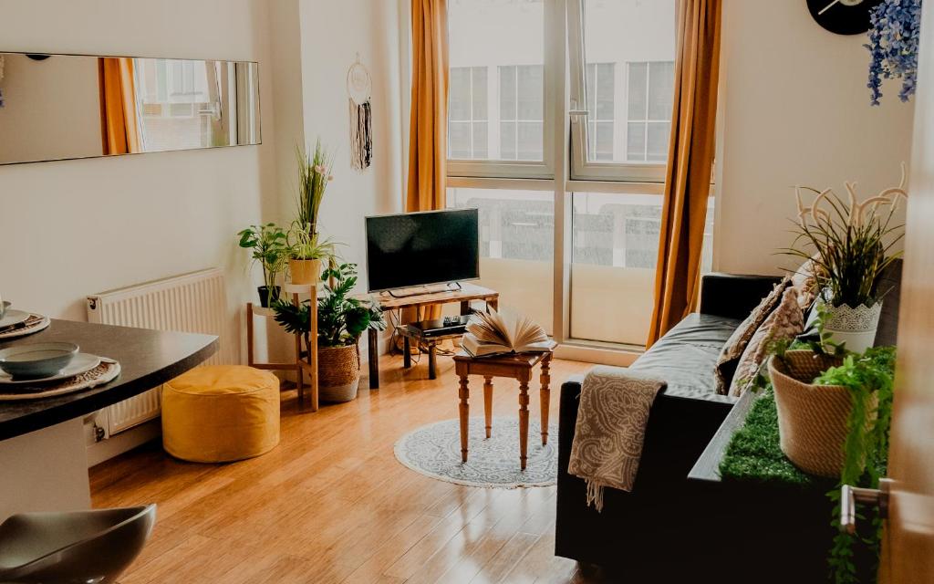 a living room with a couch and a tv at Lovely Bohemian Apartment in Heart of City Life in Glasgow