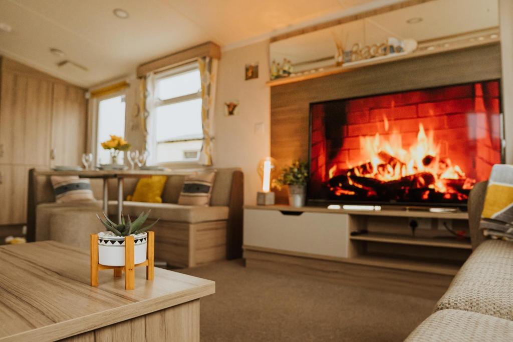 a living room with a fireplace and a couch at Cosy Caravan Craig Tara in Ayr