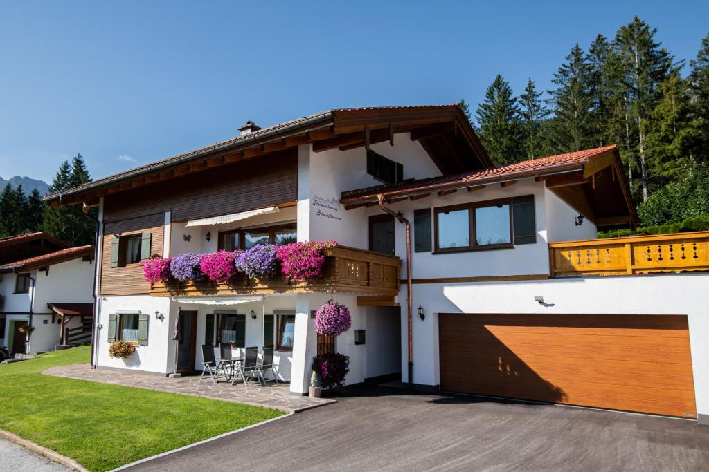 una casa con flores en los balcones y un garaje en Ferienwohnung Schnitzlbaumer, en Bischofswiesen