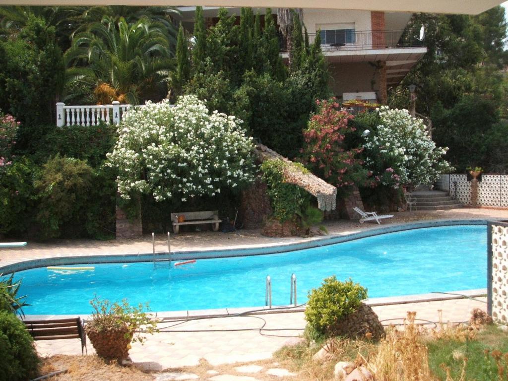 a large blue swimming pool in a yard with flowers at Casa Rural Porta Del Cel in Serra