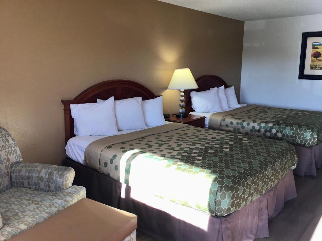 una habitación de hotel con 2 camas y una silla en SilverStone Lite, en Sunnyside