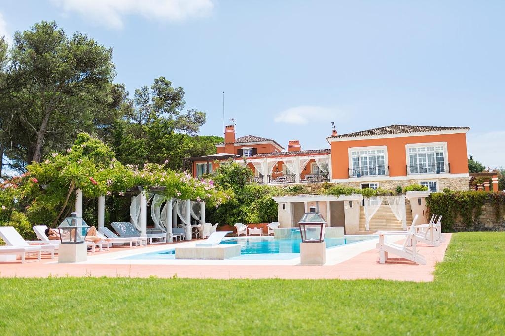 a swimming pool with chairs and a house at Quinta Tagus in Costa da Caparica