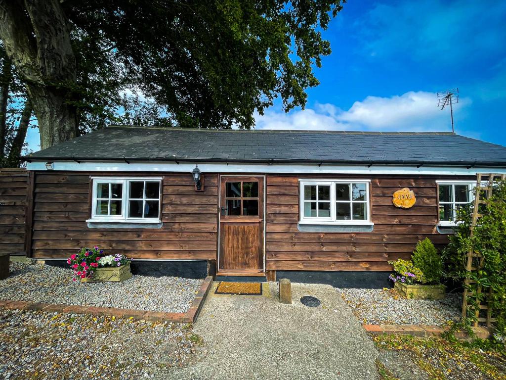 eine Holzhütte mit einer Tür und einer Veranda in der Unterkunft Holmdale Holiday Cottages in Rye