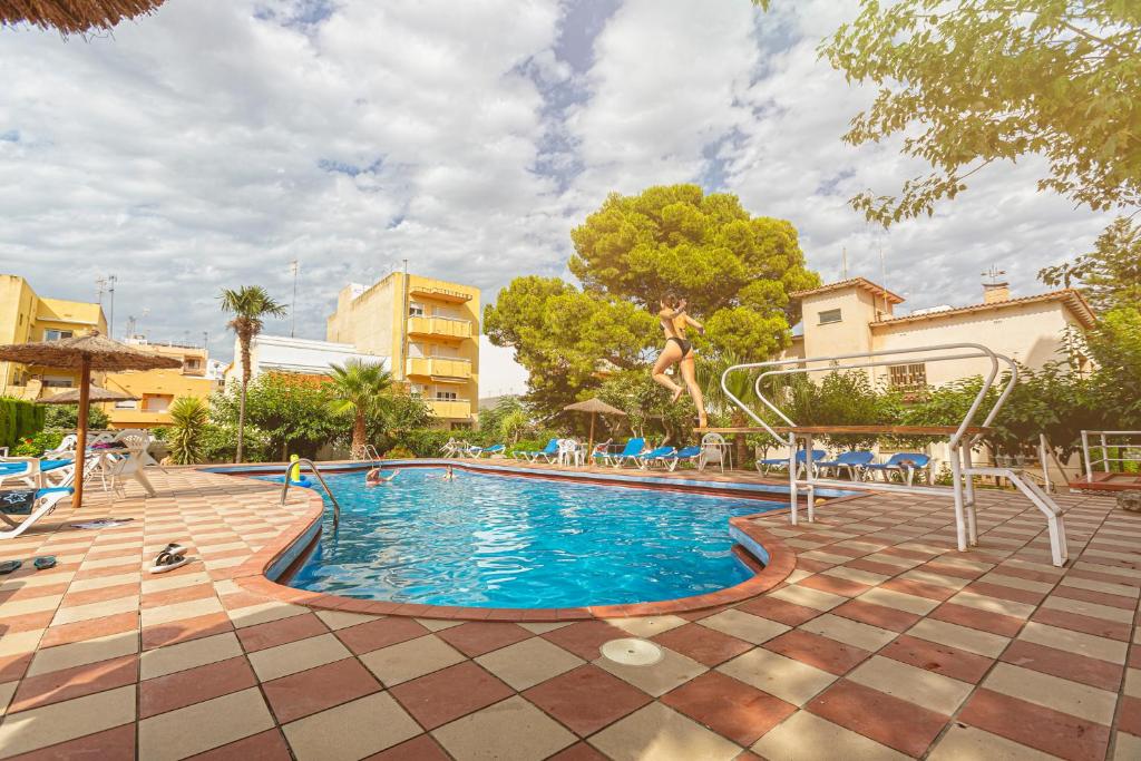 a swimming pool in a resort with chairs and trees at Apartamentos El Oasis in Benicarló