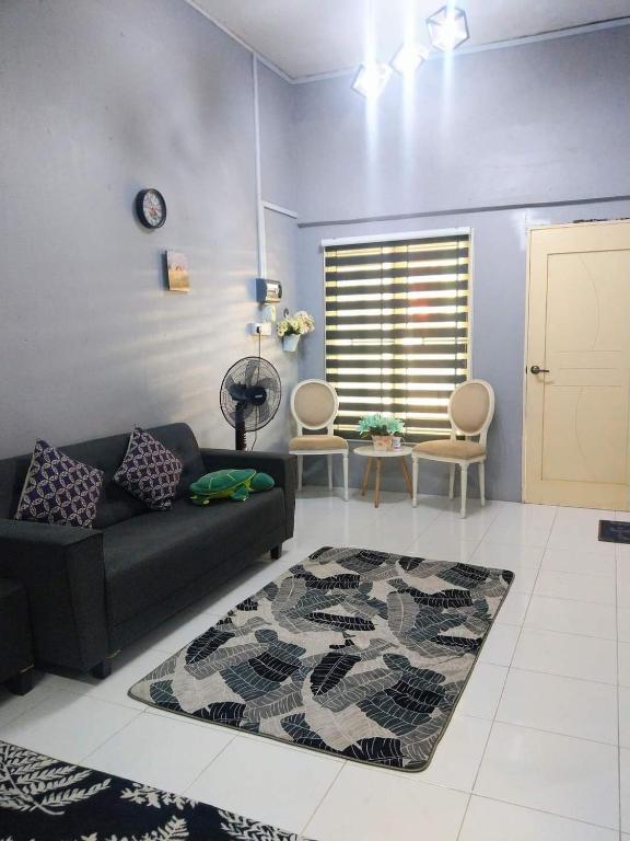 a living room with a couch and a rug at Azie Homestay in Kota Bharu