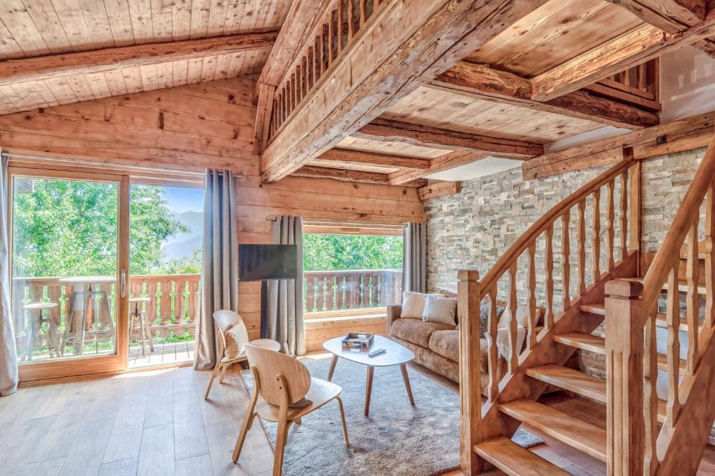 una sala de estar con techos de madera y una escalera. en Appartement La Pause de l'Ours - Welkeys, en Combloux