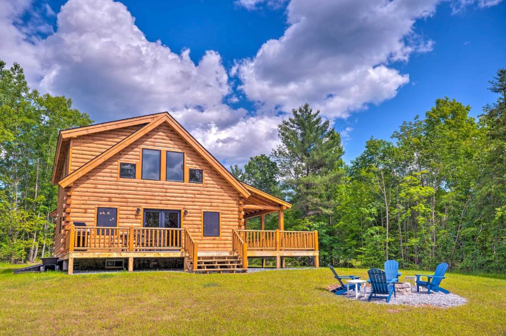 a log cabin with a deck and two chairs at Wooded North Haverhill Haven with Wood Fire Pit 