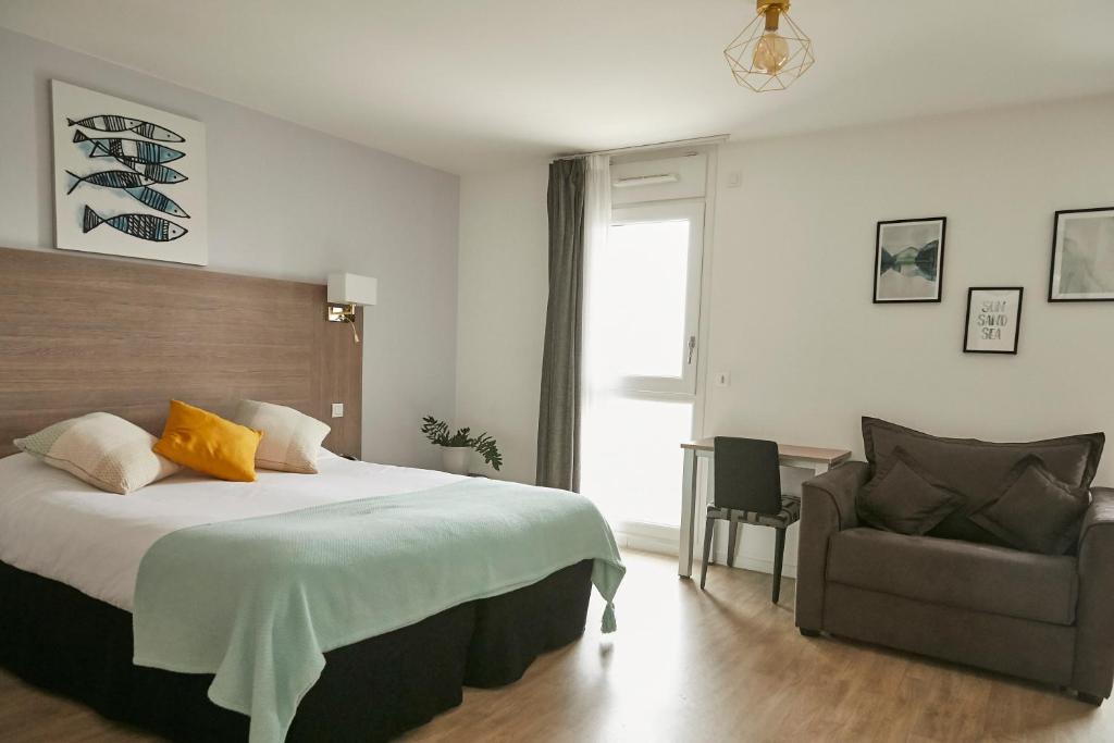 1 dormitorio con 1 cama grande y 1 silla en Tulip Inn Massy Palaiseau - Residence, en Palaiseau