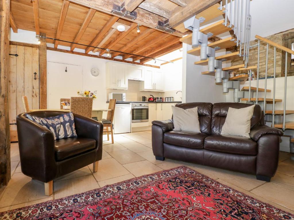 a living room with a leather couch and a chair at Nympy Cottage in Nympsfield