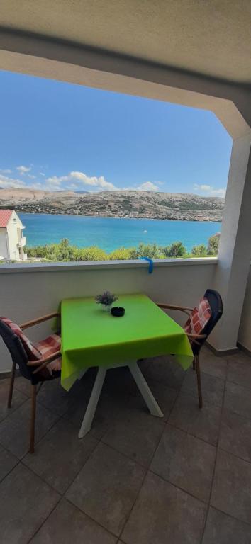 une table et des chaises vertes dans une chambre avec une grande fenêtre dans l'établissement Apartments Feniks, à Pag