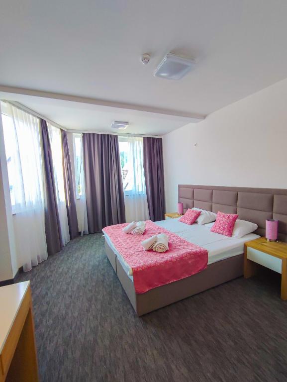 a hotel room with a large bed with pink sheets at Oaza Mira Hotel & Resort-فندق ومنتجع واحة الهدوء in Vlasic