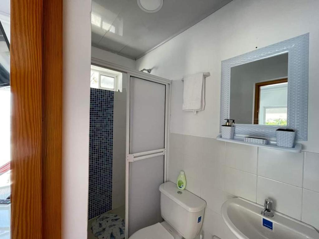 een badkamer met een toilet, een wastafel en een spiegel bij Posada Old Town Bay in Providencia