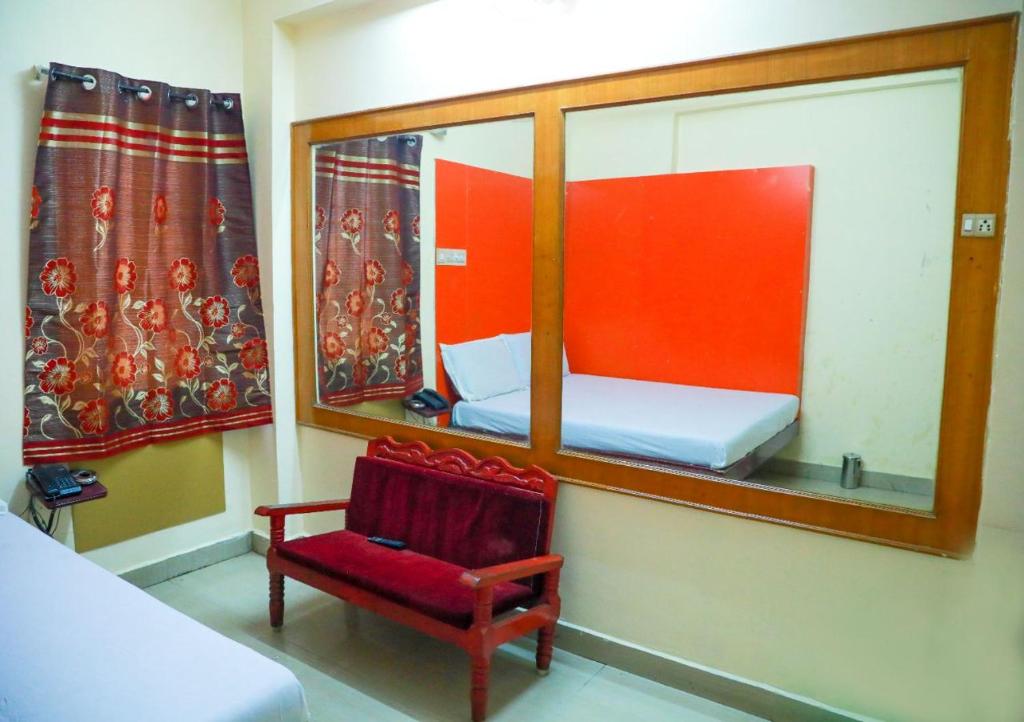 a small room with a mirror and a red chair at Hotel New West Tower in Madurai