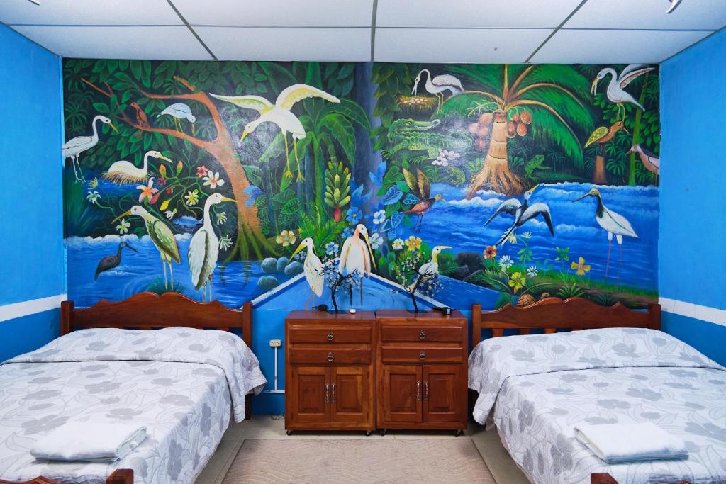 a bedroom with two beds and a mural at Hospedaje Hefziba in Moyogalpa