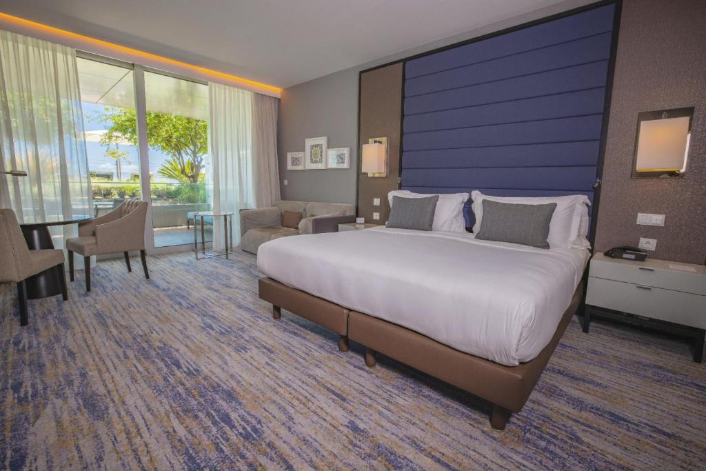 a bedroom with a large bed and a living room at InterContinental Cascais-Estoril by IHG in Estoril