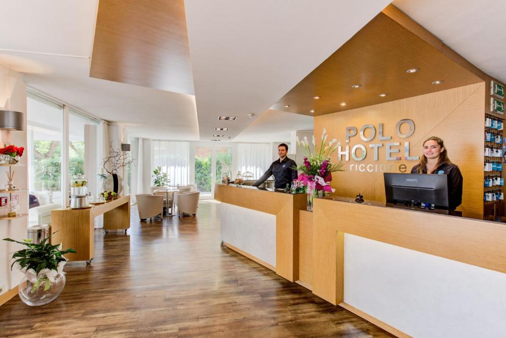un hall d'hôtel avec 2 personnes assises à un comptoir dans l'établissement BeYou Hotel Polo, à Riccione