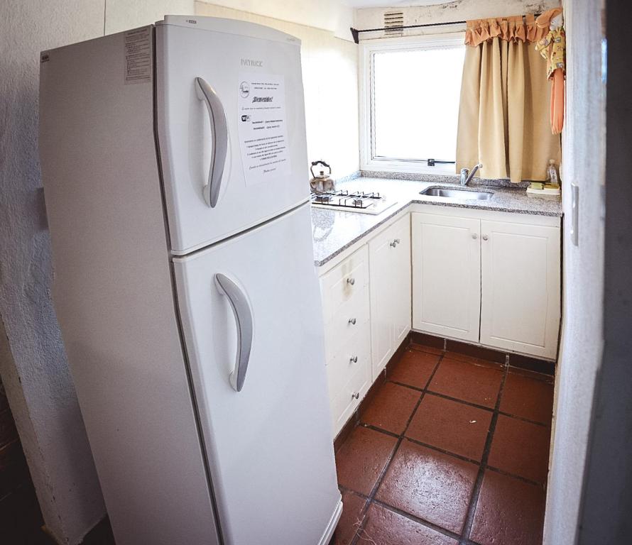 een witte koelkast in een keuken met een raam bij La Candida departamentos in Merlo