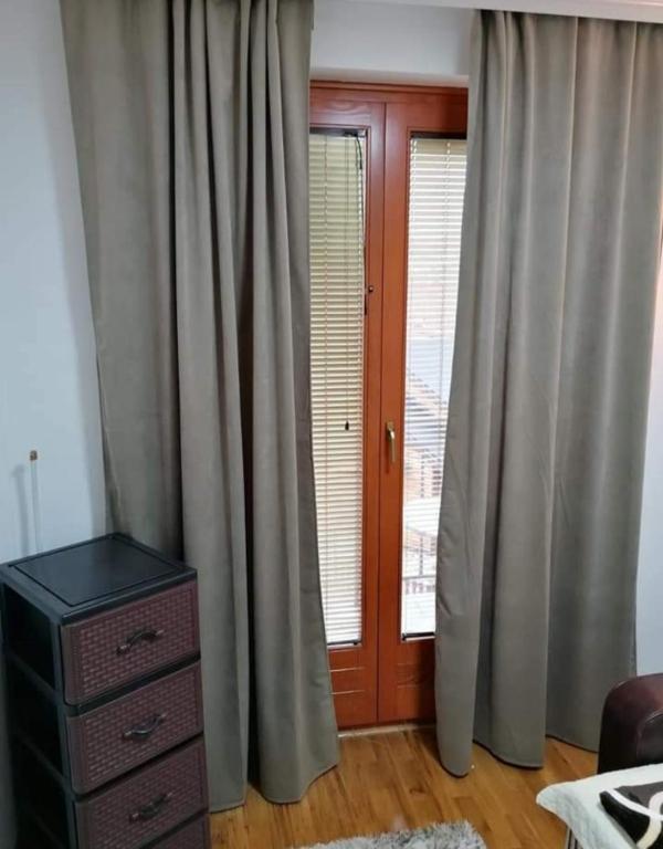 a bedroom with curtains and a dresser and a window at Apartman Elena in Vrnjačka Banja