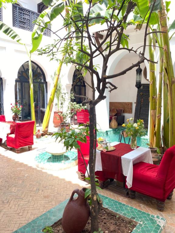 ein Restaurant mit roten Stühlen, einem Tisch und einem Baum in der Unterkunft Dar Soukaina in Marrakesch