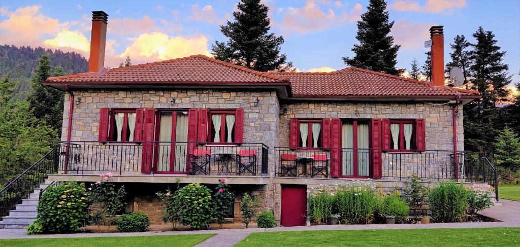 ein Haus mit roten Türen und einem Balkon in der Unterkunft Φιλοξένια Studios in Vitina