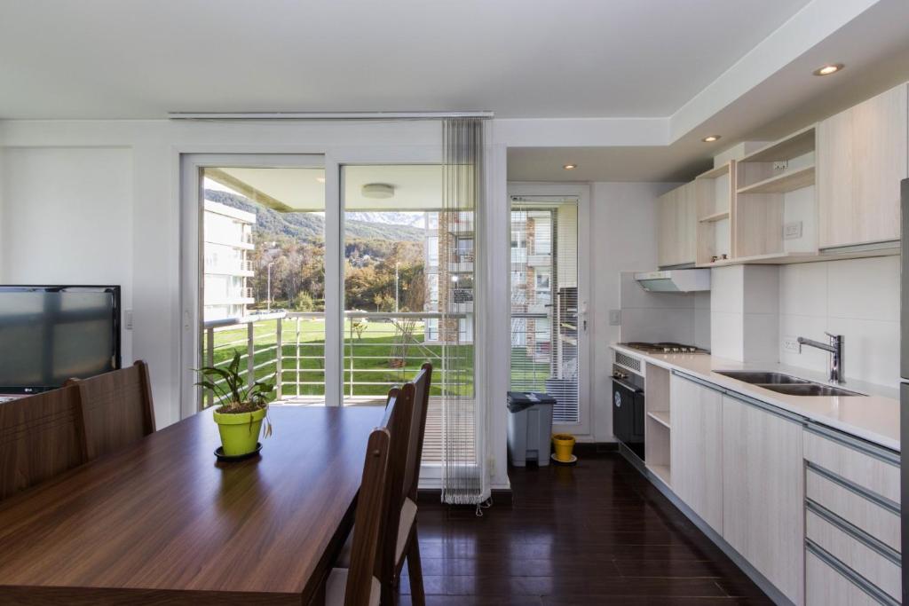 烏斯懷亞的住宿－Gray Fox Apartments Pipo，厨房配有木桌和大窗户。