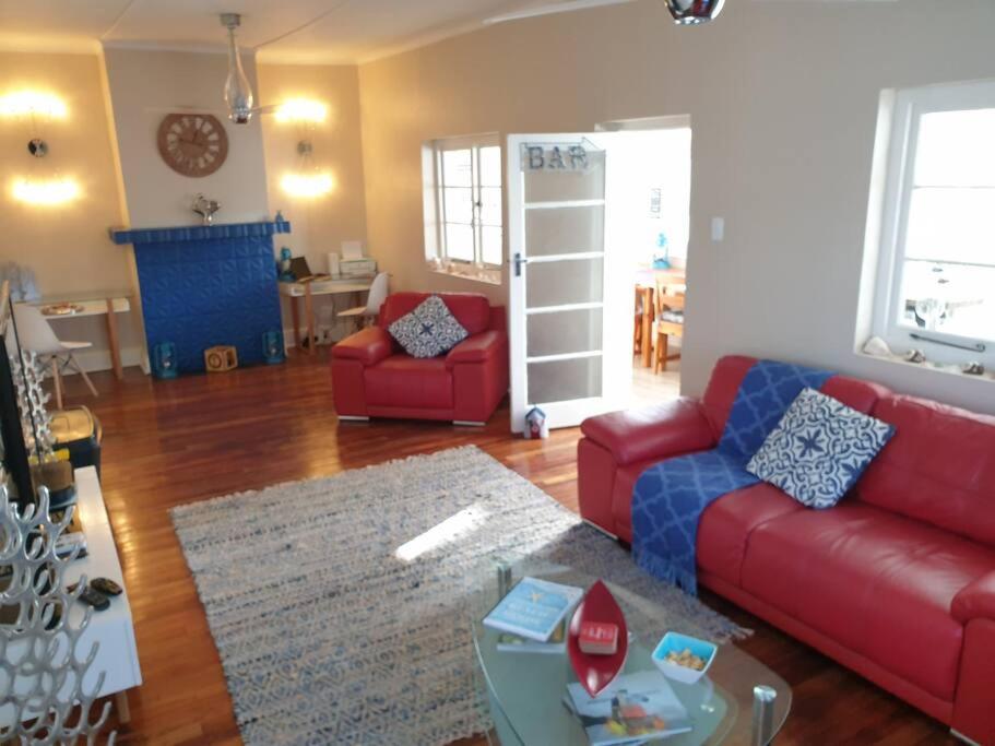 ein Wohnzimmer mit einem roten Sofa und einem Tisch in der Unterkunft Beach House with DSTV & WIFI & basic housekeeping in Knysna