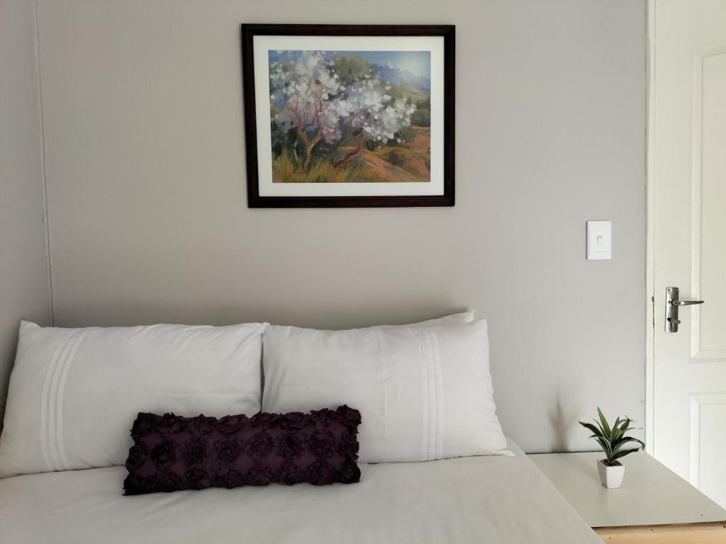 um sofá branco com uma pintura de flores na parede em The Terrace Guest House em Roodepoort