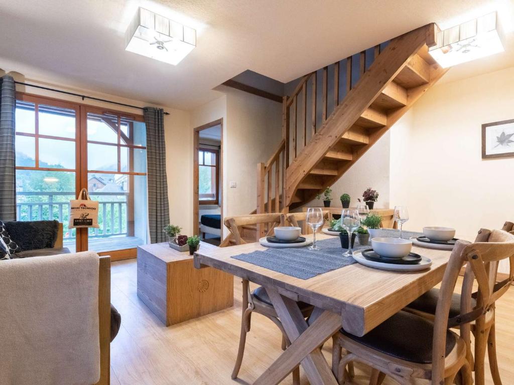 ein Esszimmer und ein Wohnzimmer mit einem Holztisch und einer Treppe in der Unterkunft Appart centre Saint-Lary avec piscine, sauna et parking - FR-1-296-425 in Saint-Lary-Soulan
