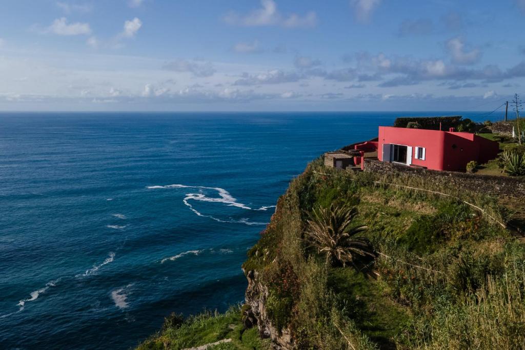 una casa rossa su una scogliera vicino all'oceano di Casa do Cascalho a Ribeira Grande