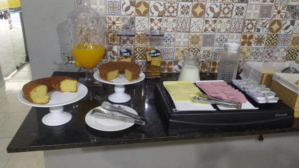 a table with two plates of food and orange juice at Orquidário Praia Hotel in Santos